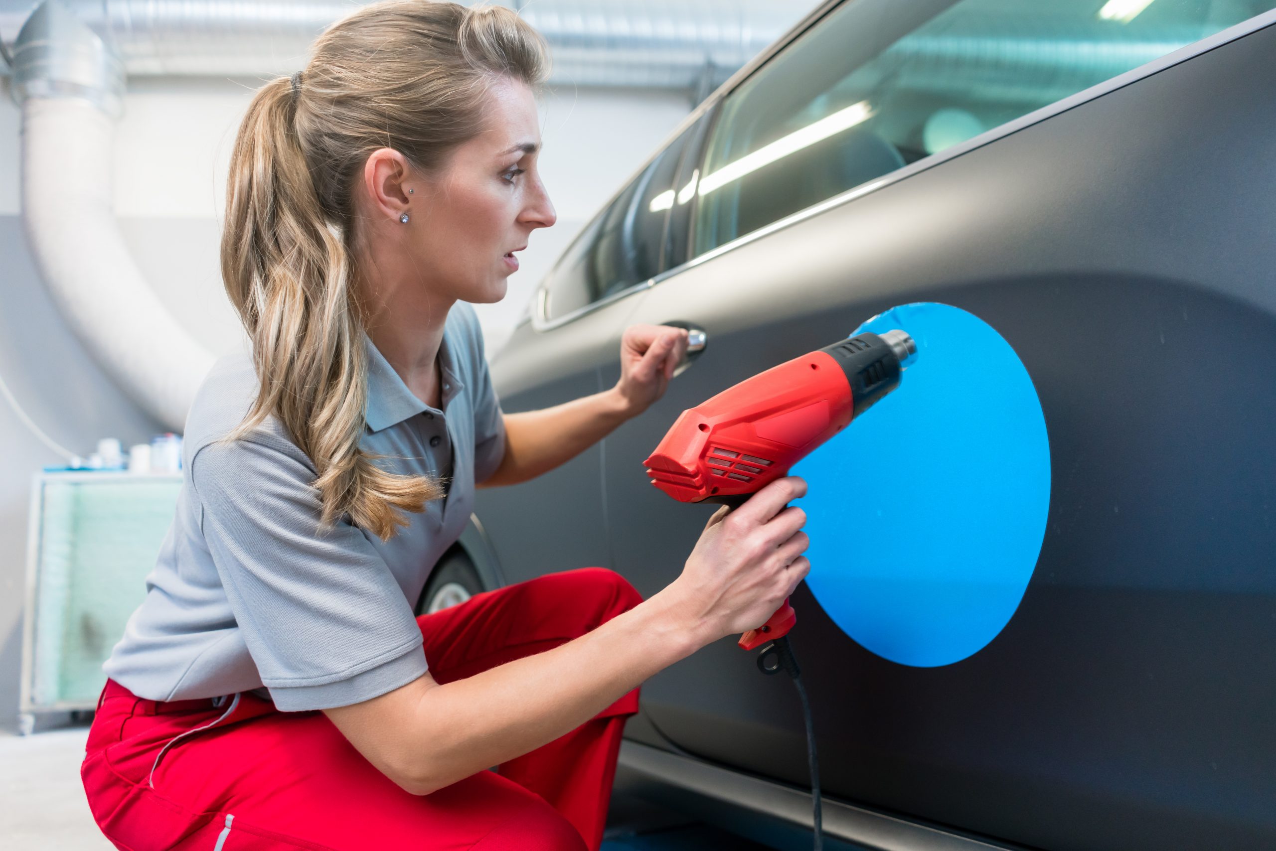 Woman putting sticker with company slogan on a car